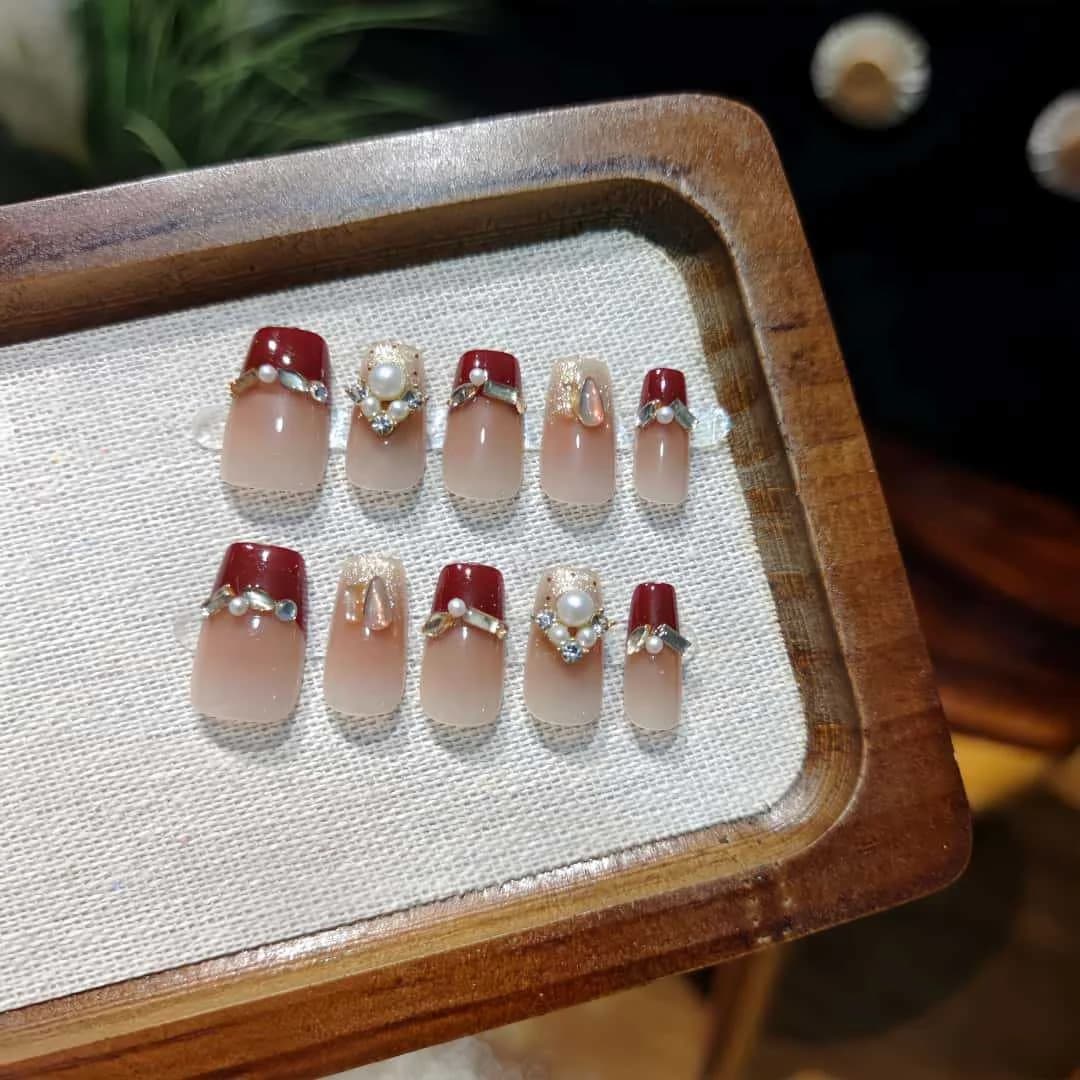 ציפורניים מלאכותיות אדומות עם פנינים ונצנצים, צורת קופין קצרה עם טיפ צרפתי